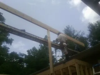 Carpenter setting a ridge beam over a new addition frame — Ice Dam Removal by Roofing Brothers in Absarokee
