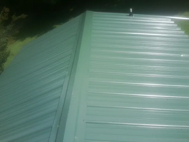 New green metal panels meeting at the ridge of a roof — Flat Roof Repair work by our crew in Absarokee