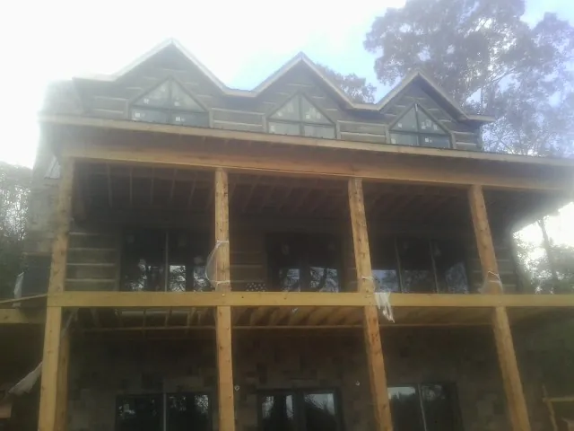 Dormers and porch framing on a large log home under construction — Roof Coating work by our crew in Absarokee