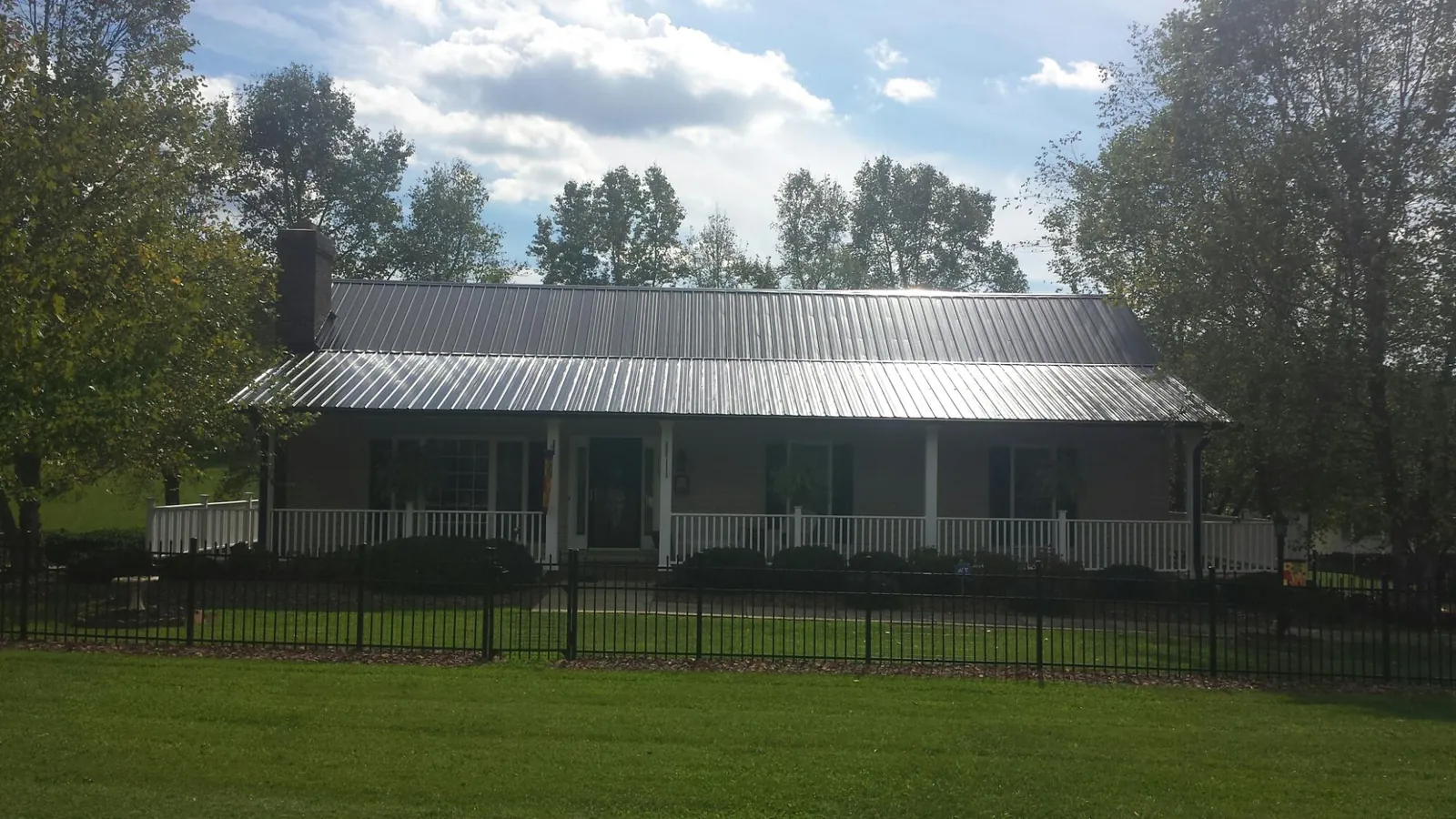 Gray metal roof on a brick ranch with a full width front porch — Gutter Guard Installation work by our crew in Absarokee