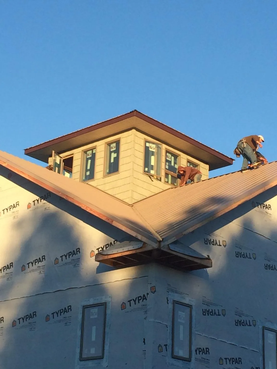 Roofers working around a rooftop cupola on a new metal roof at sunset — Roof Waterproofing in Absarokee by Roofing Brothers
